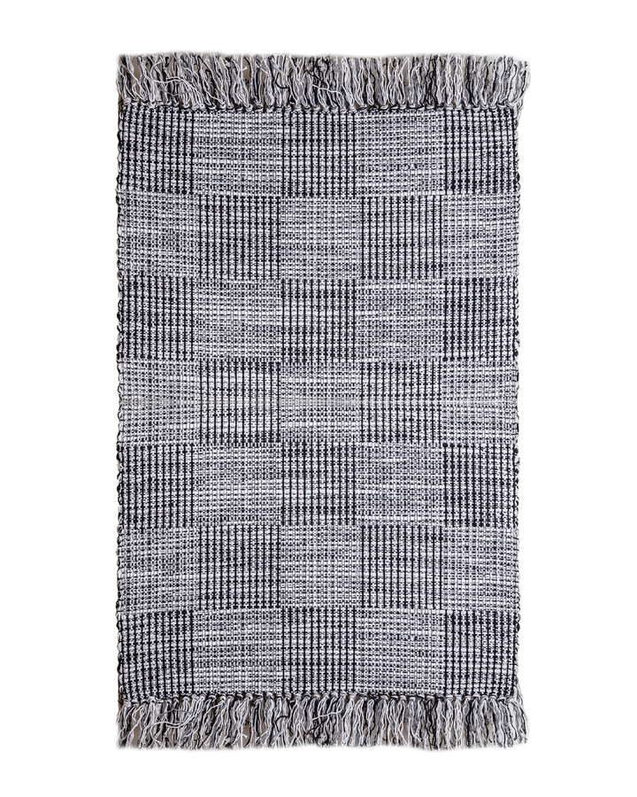 Svart trasmatta i mjuk bomull placerad på trägolv i ett modernt hem