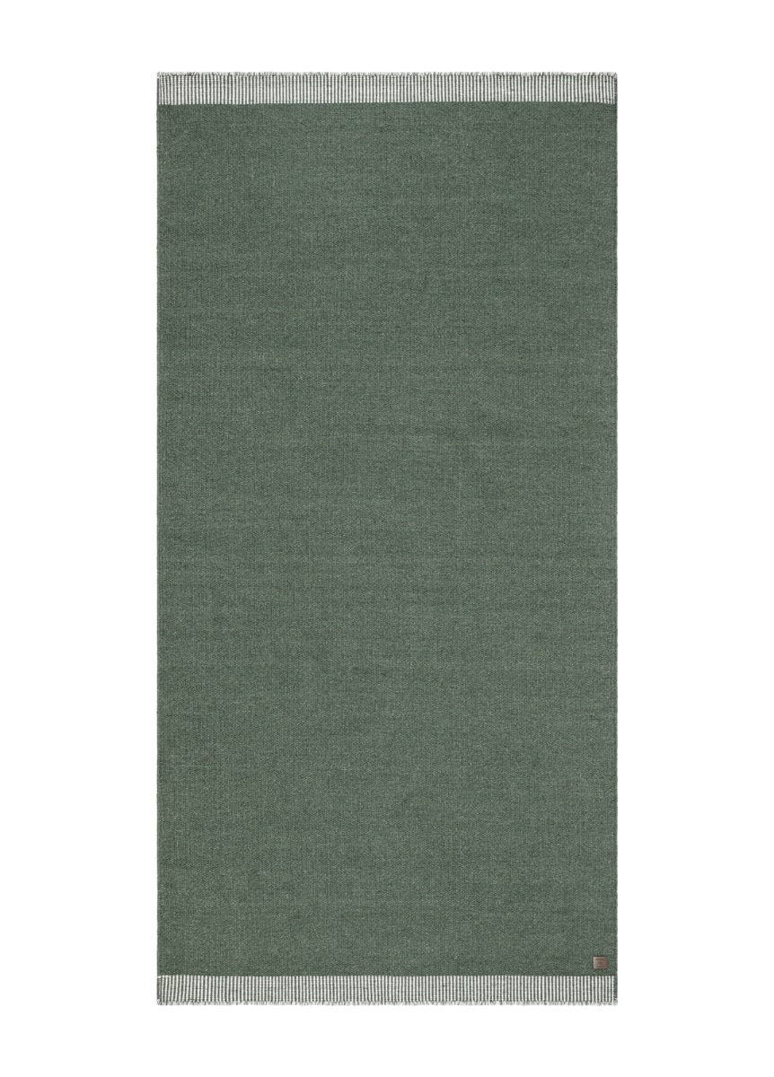 Grön handvävd ullmatta Rachel med diskret dekorationskant och mjuk struktur