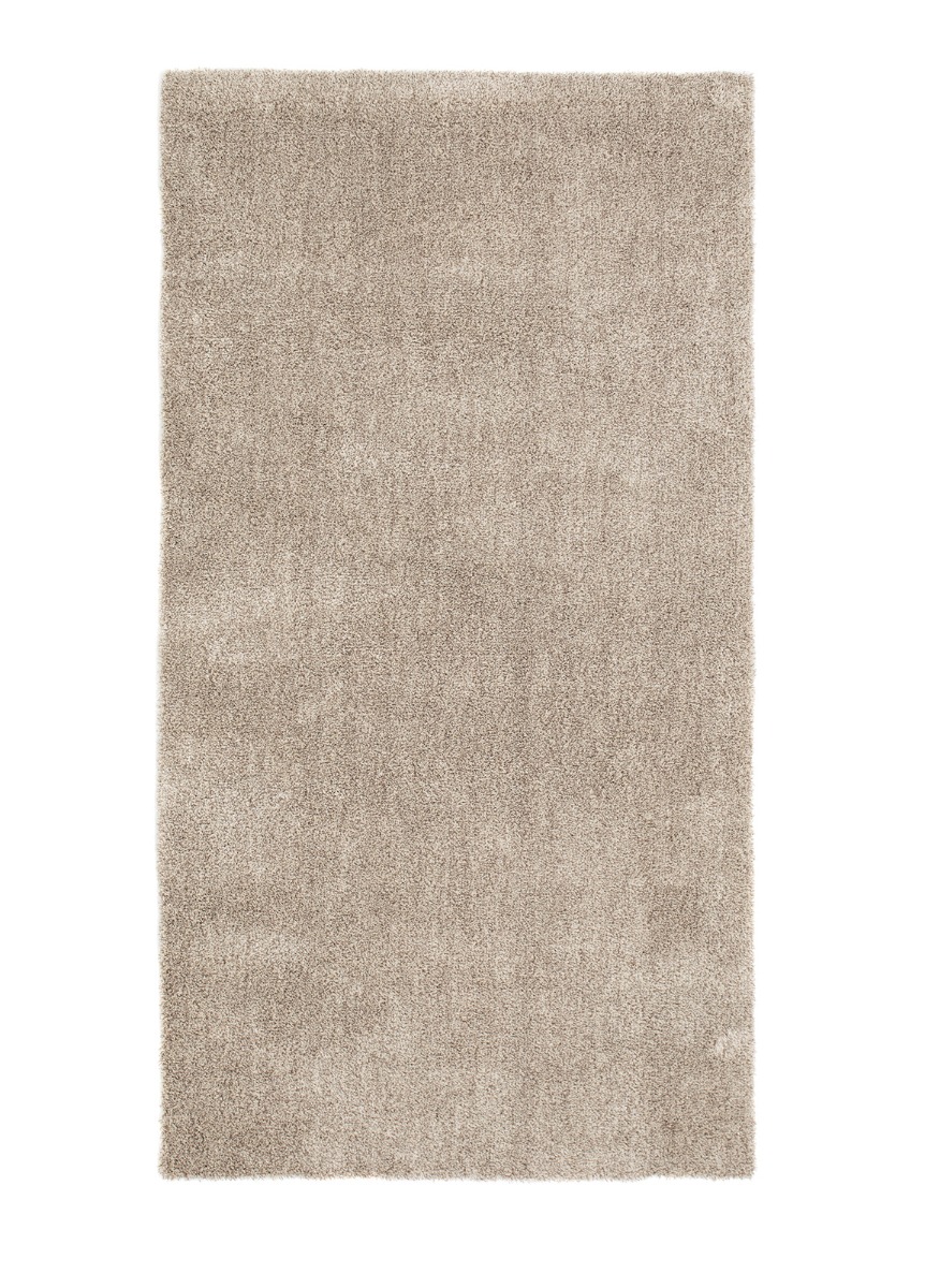 Närbild av mjuk melerad ryalöpare i linnefärg med fluffig yta och filtbaksida på trägolv