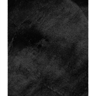 Svart mjuk ryamatta med lång lugg och antydan till glans på trägolv