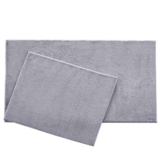 Två silverfärgade badrumsmattor i mjuk polyester på vitt badrumsgolv