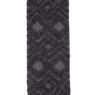 Grå fluffy bomullsmatta med hög lugg och dekorativa fransar på kortsidor, placerad på golvet i ett modernt rum